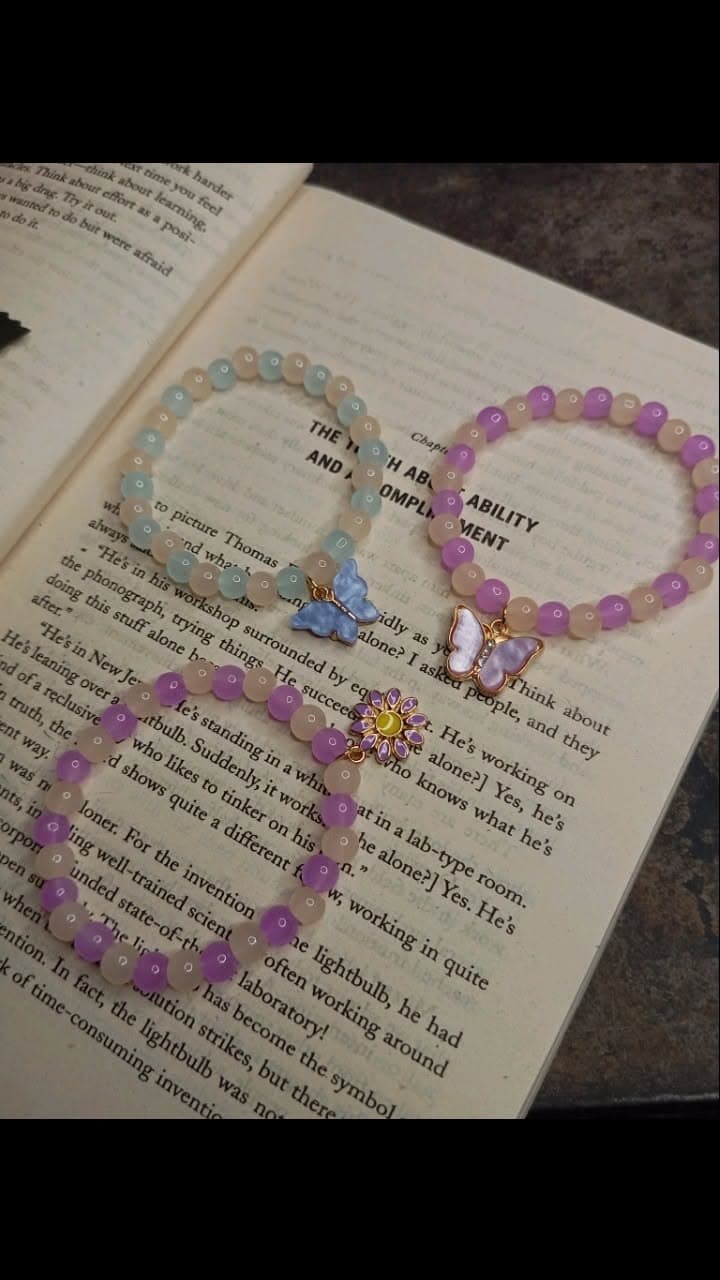 Beaded bracelets with butterfly and daisy charms on an open book