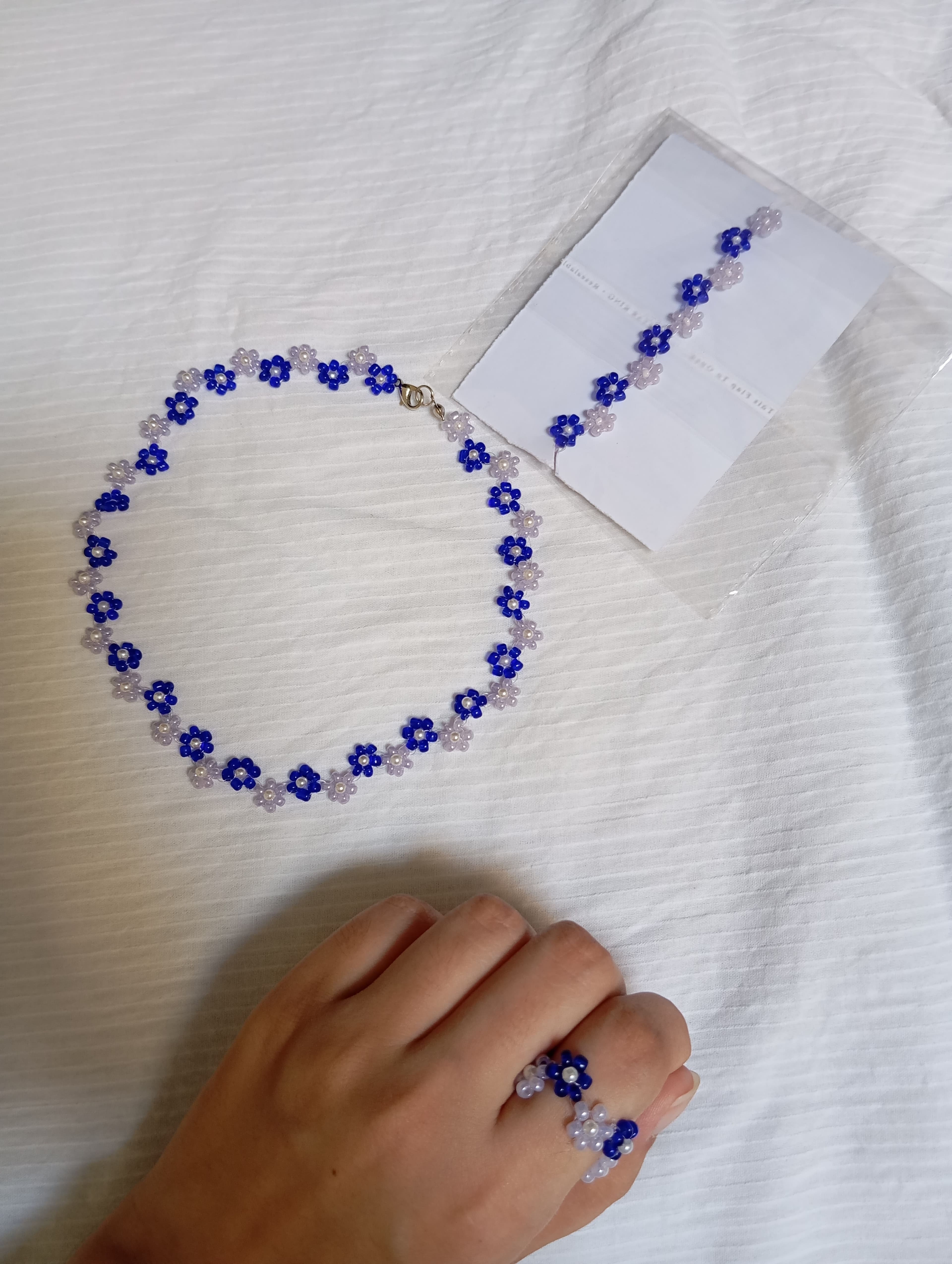 Cobalt Daisy Necklace with matching bracelet and ring on white sheet