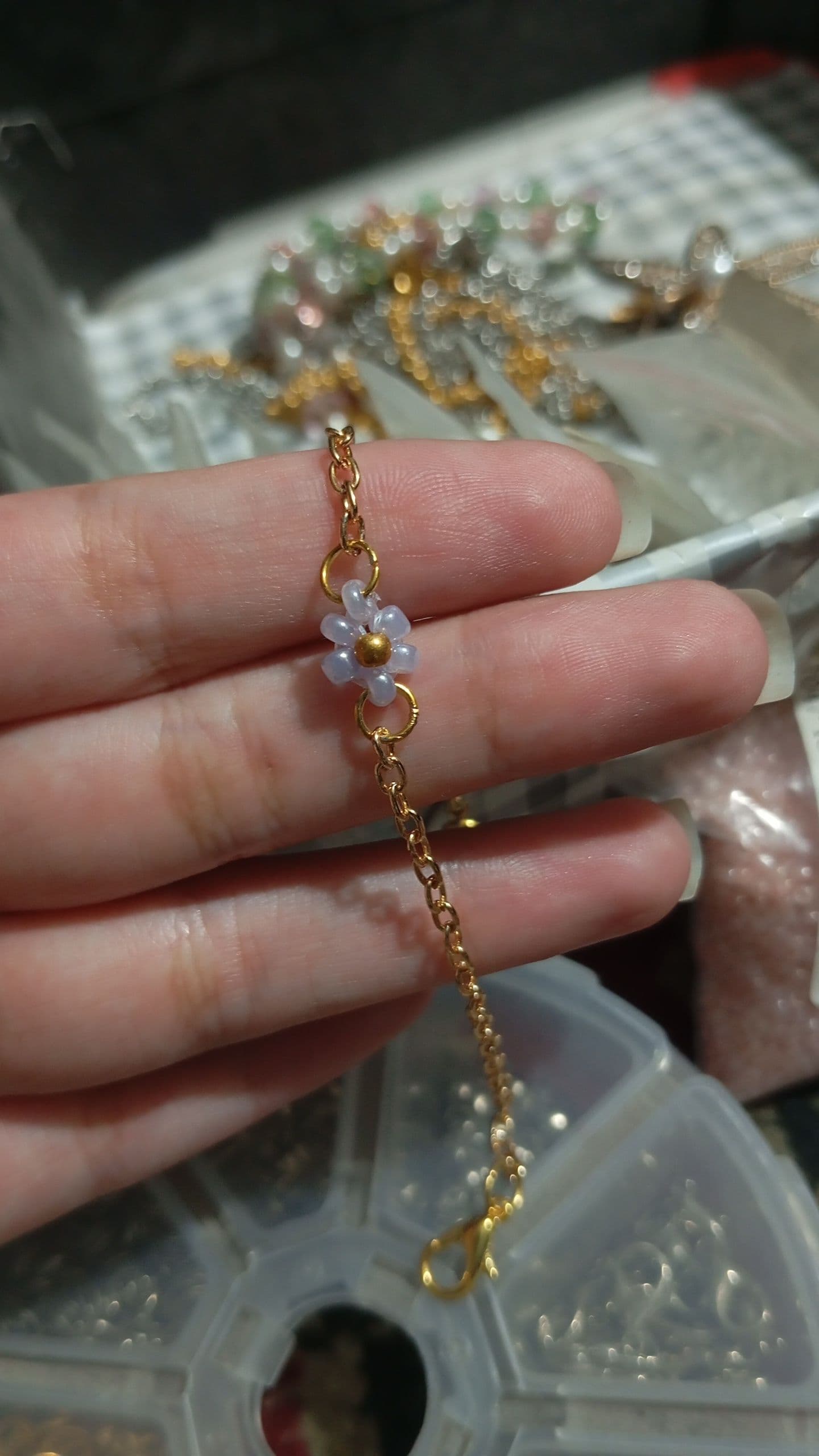 Daisy Charm Chain Bracelet held in hand over a bead organizer